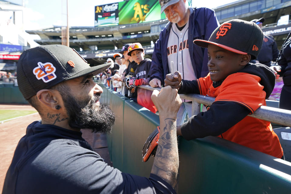 San Francisco Giants pitcher Sergio Romo greets King Vincent, 7, of San Leandro, Calif., before the start of a spring training baseball game against the Oakland Athletics in Oakland, Calif., Sunday, March 26, 2023. The Giants plan to have Romo pitch on Monday at Oracle Park to mark his retirement. (AP Photo/Eric Risberg)