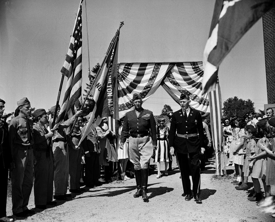 Gen. George S. Patton Jr., escorted by Legionnaire John H. Ostrom, arrives at Hamilton, Mass. for a hometown celebration, June 24, 1945. The general marches between Boy and Girl Scouts who lined his pathway.