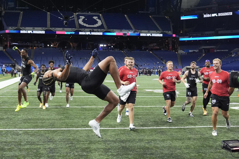 El receptor abierto de Washington, Roma Udonze, hace una voltereta hacia atrás mientras los jugadores celebran después de su entrenamiento en el NFL Scouting Combine, el sábado 2 de marzo de 2024, en Indianápolis.  (Foto AP/Michael Conroy)