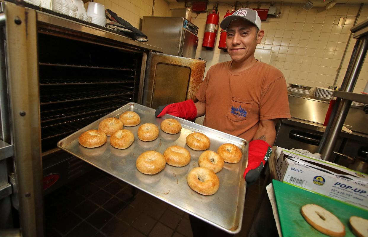 Owner Margarilo Coria pulls a rack of bagels out from the oven early Thursday morning, Dec. 15, 2022, at De Coria's Bagel Shop at 609 N. Main St. in Belmont.