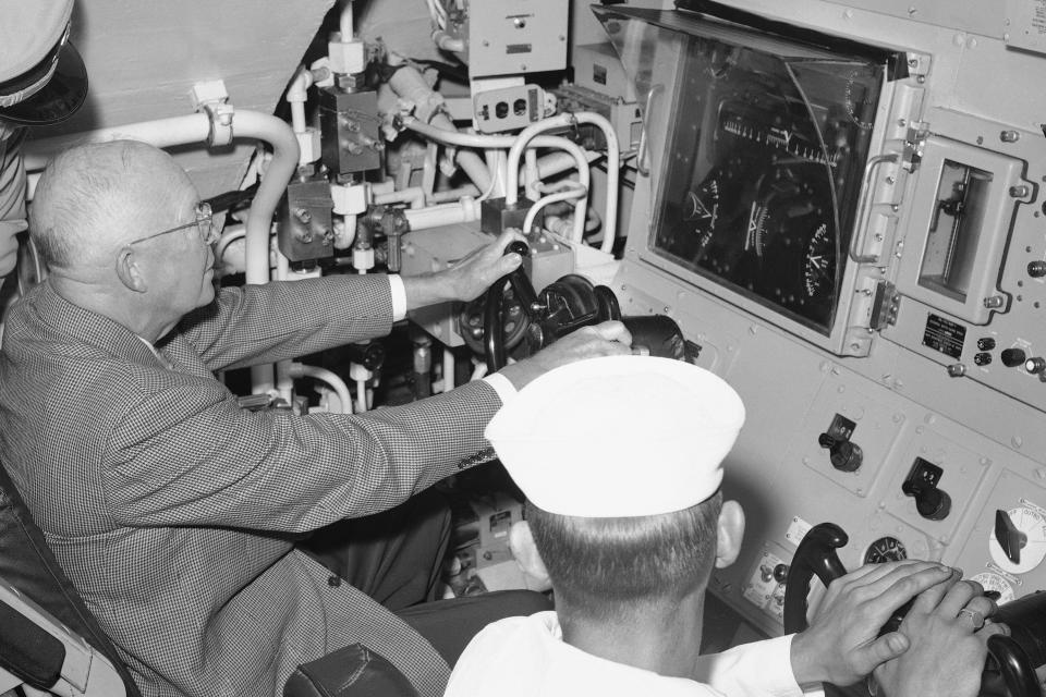 FILE - President Dwight Eisenhower tries his hand at the controls of the USS Patrick Henry ballistic missile submarine during a tour at Newport, R.I., on July 26, 1960. William Burr, a senior analyst at the nonprofit National Security Archive at George Washington University, says during the late 1950s, Eisenhower and his advisers worried about the U.S.’s vulnerability to a nuclear surprise attack. So the president could make quick decisions on the spot, a military aide started carrying a satchel of documents that would help the president communicate with the Pentagon or other military headquarters. (AP Photo/CPG, File)