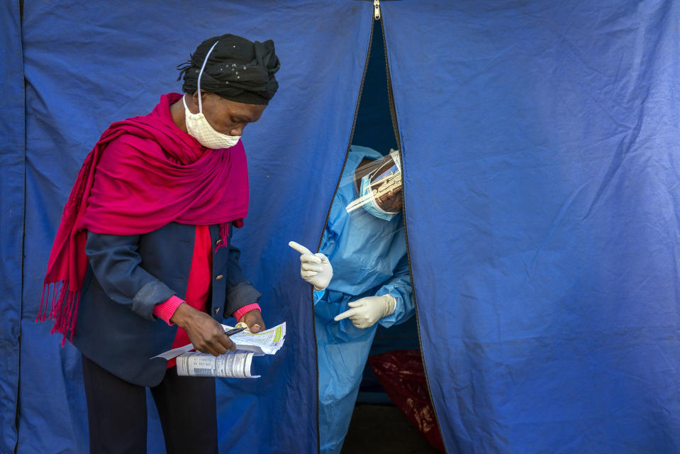 Una enfermera da instrucciones a una mujer tras entregarle material para hacerse pruebas de coronavirus, VIH y tuberculosos en Johannesburgo el 30 de abril del 2020. (AP Photo/Jerome Delay)