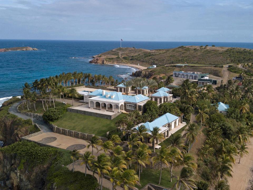 A palatial home is seen on an island surrounded by blue water.