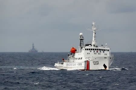 A Chinese Coast Guard vessel (R) passes near the Chinese oil rig, Haiyang Shi You 981 (L) in the South China Sea, about 210 km (130 miles) from the coast of Vietnam in this June 13, 2014 file photo. China claims about nine-tenths of the South China Sea but insists it wants a peaceful resolution to the conflict. REUTERS/Nguyen Minh/Files