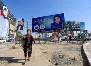 Election posters of parliamentary candidates are installed on a street while a boy walks past in Jalalabad, Afghanistan October 6, 2018. REUTERS/Parwiz