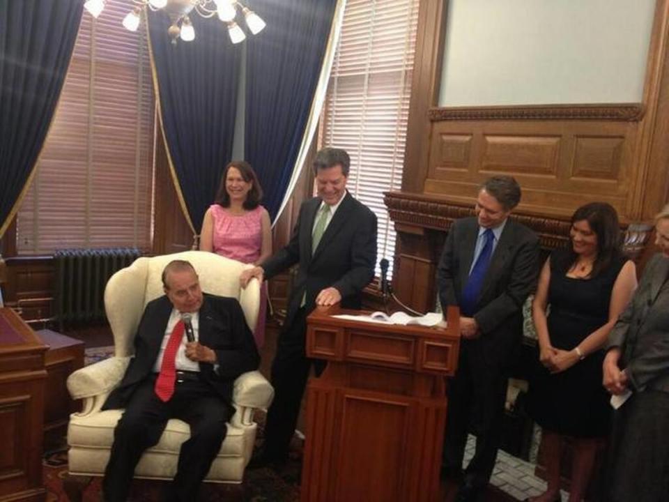 Gov. Sam Brownback smiles as former Sen. Bob Dole speaks during a ceremony in which Brownback officially filed for re-election May 15, 2014.