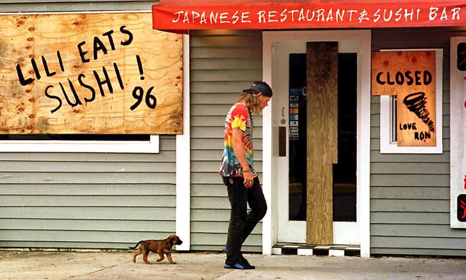 A Key West man and his puppy walk past the boarded-up Yo Sake Japanese Restaurant and Sushi Bar on Duval Street. It was one of the few businesses to board up for Hurricane Lili in October 1996.