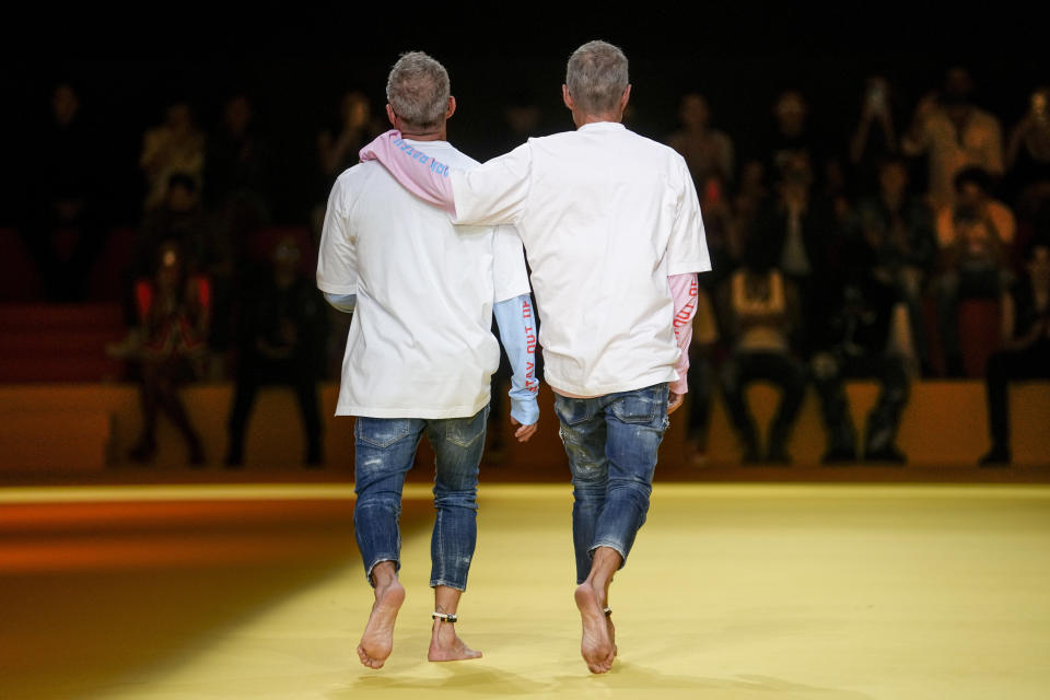 Designers Dean Caten, left, and Dan Caten accept applause at the end of the Dsquared2 men's Spring Summer 2023 collection presented in Milan, Italy, Friday, June 17, 2022. (AP Photo/Luca Bruno)