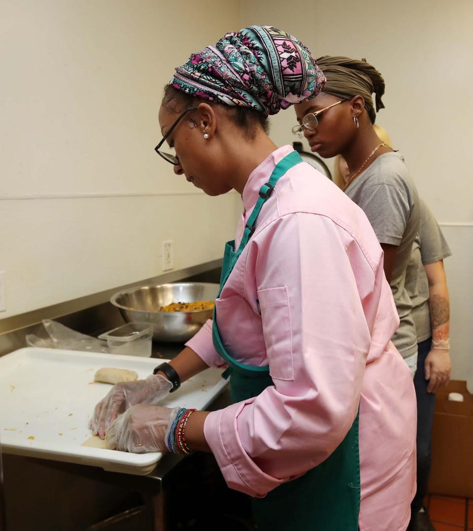 House of Tacos owner Chanell Cook shows students how to make jerk soul rolls during on-site restaurant training in the kitchen at NoHi as part of Jump On Board for Success' (JOBS) culinary program in Akron.