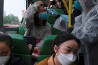 A resident wearing mask and raincoat volunteers to take temperature of passenger following the outbreak of a new coronavirus at a bus stop at Tin Shui Wai, a border town in Hong Kong