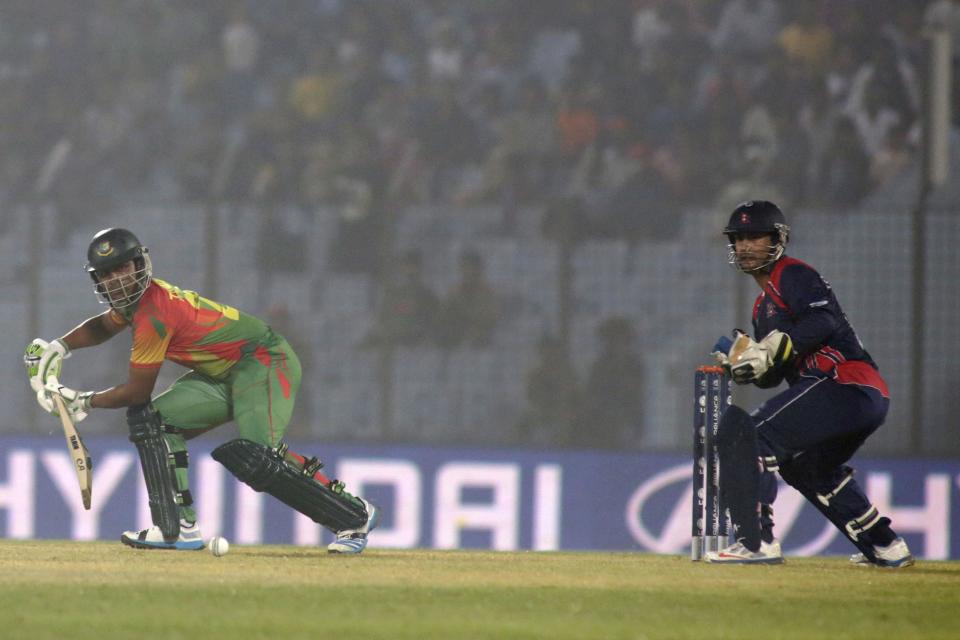 Bangladesh's Tamim Iqbal, left, plays a shot as Nepal's wicketkeeper Subash Khakurel watches during their ICC Twenty20 Cricket World Cup match in Chittagong, Bangladesh, Tuesday, March 18, 2014. (AP Photo/Bikas Das)