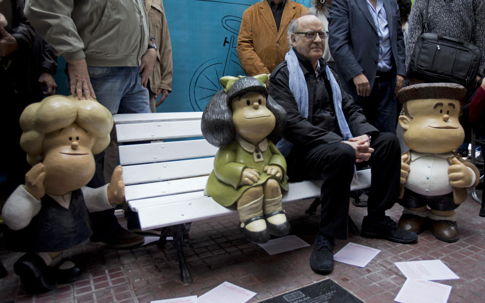 FILE - In this Sept. 29, 2014 file photo, Argentine cartoonist Joaquin Salvador Lavado, better known as "Quino," who created the comic strip Mafalda, poses for a photo with statues of the strip's characters, Susanita, left, Mafalda, center, and Manolito, during a 50th-anniversary celebration in Buenos Aires, Argentina. Lavado passed away on Wednesday, Sept. 30, 2020, according to his editor Daniel Divinsky who announced it on social media. (AP Photo/Eduardo Di Baia, File)