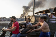 FILE - In this Aug. 4, 2020 file photo, wounded people are evacuated as smoke rises from a massive explosion in Beirut, Lebanon. A year after the Aug. 4 deadly blast at Beirut port, families of the victims are consumed with winning justice for their loved ones and punishing Lebanon's political elite, blamed for causing the disaster through their corruption and neglect. (AP Photo/Hassan Ammar, File)