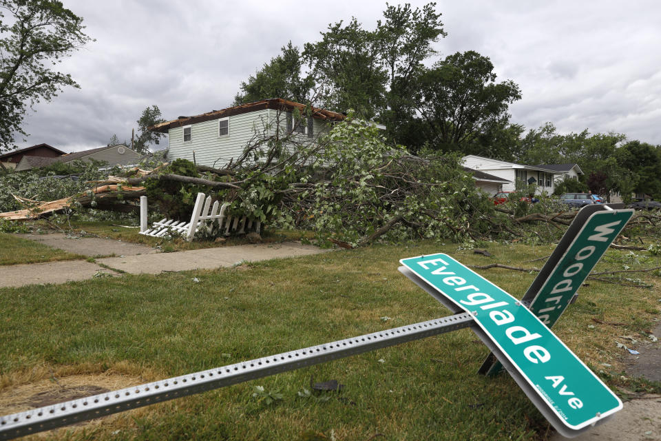 A fallen street sign lays on the ground near a damaged home after a tornado passed through the area on Monday, June 21, 2021, in Woodridge, Ill. (AP Photo/Shafkat Anowar)