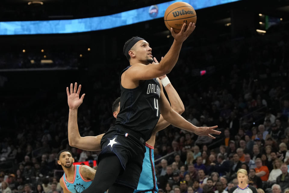 Orlando Magic guard Jalen Suggs (4) drives past Phoenix Suns guard Devin Booker during the first half of an NBA basketball game, Thursday, March 16, 2023, in Phoenix. (AP Photo/Rick Scuteri)