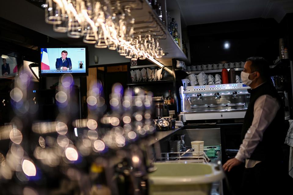 Emmanuel Macron ist auf einem Bildschirm eines Fernsehers in einem Café zu sehen, während er sich in einer TV-Ansprache an die Nation wendet. (Bild: Christophe Simon/AFP/dpa)