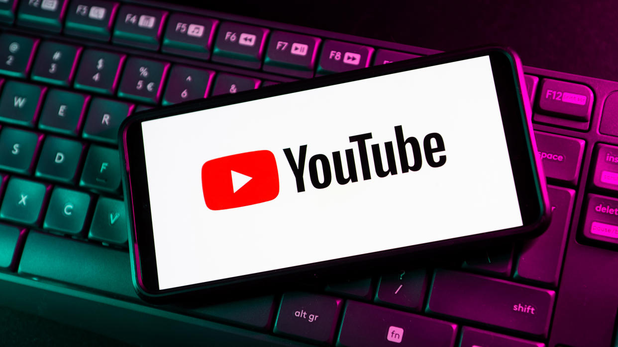  The YouTube logo appears on a phone on top of a keyboard 