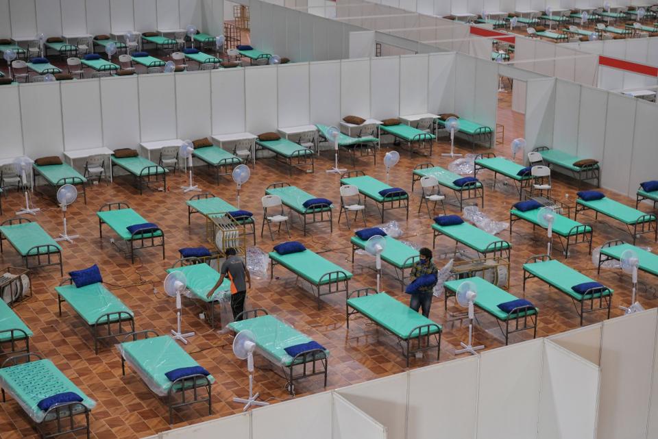 Workers prepare beds at a COVID Care Centre with the capacity of 10,100 beds inside the Bangalore International Exhibition Centre (Photo by MANJUNATH KIRAN/AFP via Getty Images)