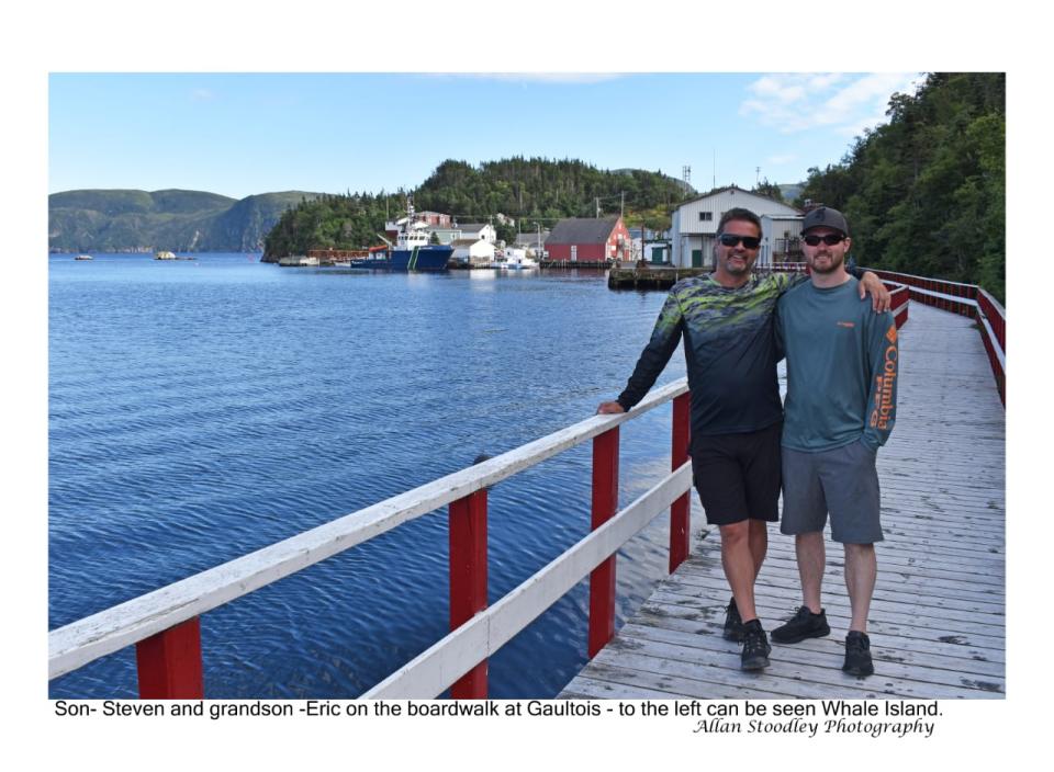 Allan Stoodley's son Steven and grandson Eric stand on the wooden boardwalkin Gaultois that joins the Room with the Point (the most populated part of the town) across the harbour. Whale Island can be seen to the left.
