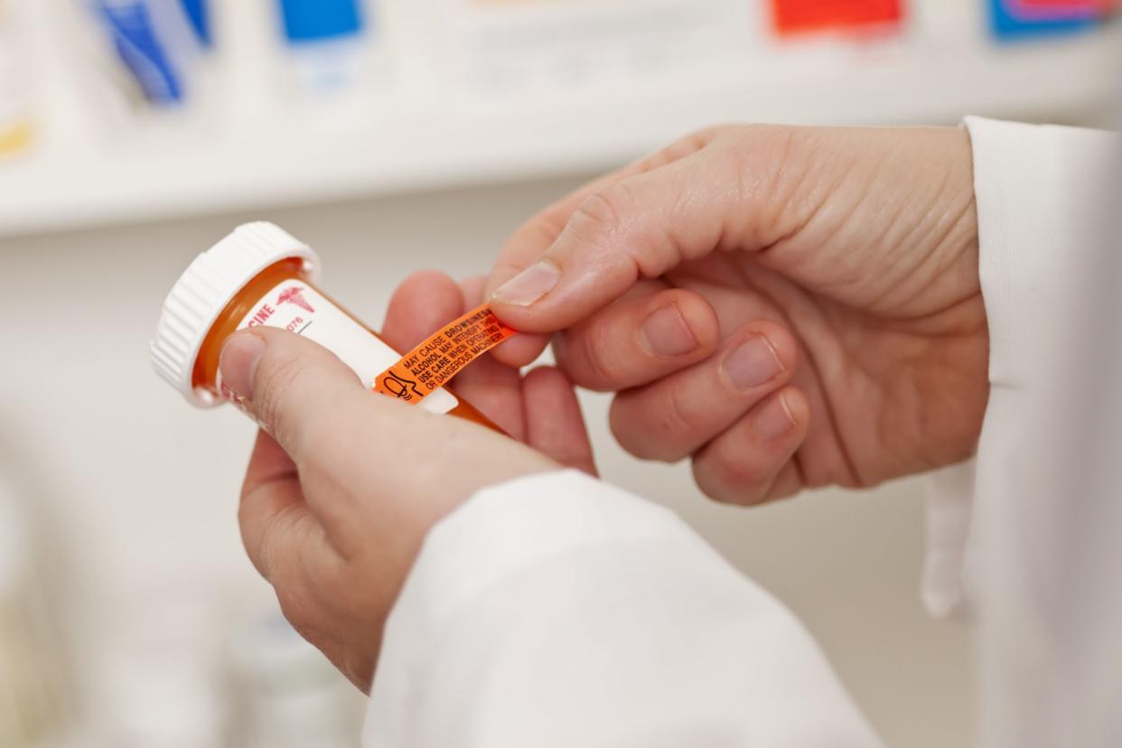 pharmacist putting sticker on medication bottle