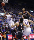 Kansas guard Remy Martin (11) attempts to score against Texas Tech guard Clarence Nadolny (3) and forward Bryson Williams (11) as Kansas forward Mitch Lightfoot (44) looks on during the first half of an NCAA college basketball game on Monday, Jan. 24, 2022 in Lawrence, Kan. (AP Photo/Colin E. Braley)