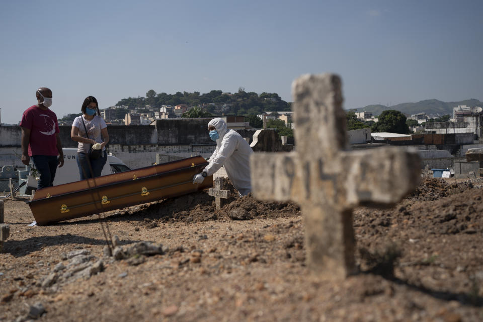 Rodrigo Bessa, left, attends the burial of his mother Edenir Rezende Bessa, who is suspected to have died of COVID-19, in Rio de Janeiro, Brazil, Wednesday, April 22, 2020. After visiting 3 primary care health units she was accepted in a hospital that treats new coronavirus cases, where she died on Tuesday. (AP Photo/Leo Correa)