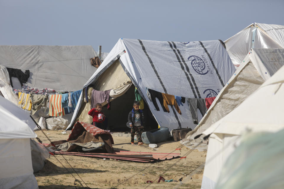 Palestinian children displaced by Israeli air and ground offensive on the Gaza Strip walk through a temporary tent camp near Kerem Shalom crossing in Rafah, Sunday, Jan. 14, 2024. (AP Photo/Hatem Ali)