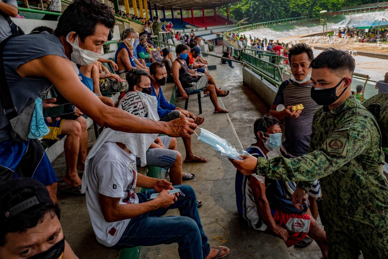A policeman hands out face masks to people who were arrested for not wearing face masks while being detained at a stadium on July 8, 2020, in Quezon city, Metro Manila, Philippines. President Rodrigo Duterte expressed concern with reopening the country as it struggles to contain the spread of the coronavirus. With more than 45,000 cases and more than a thousand deaths, the Philippines is the second worst coronavirus-hit country in Southeast Asia, despite imposing the longest lockdown in the world surpassing a hundred days that has left millions of Filipinos jobless and hungry.