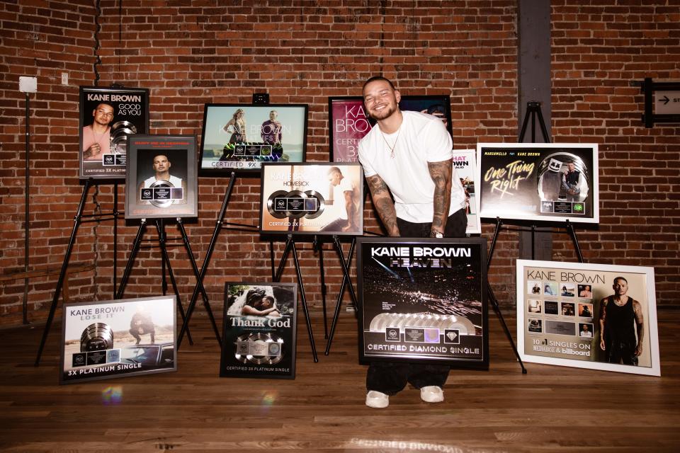 Kane Brown pictured with various honors signifying nearly 50 million albums and singles sold in the past decade of his career