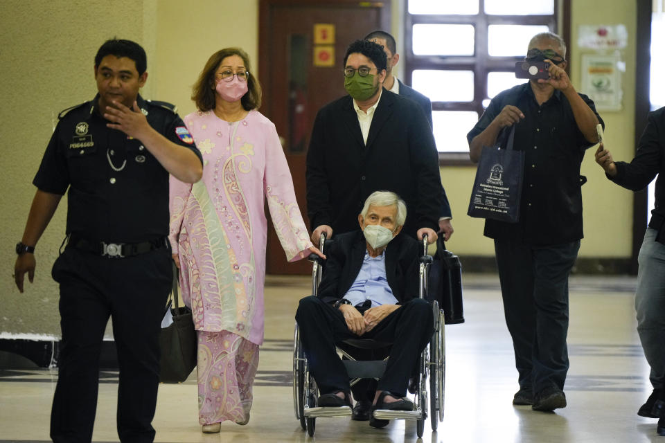 Former Malaysian Finance Minister Daim Zainuddin on wheelchair leaves the courthouse in Kuala Lumpur, Malaysia Monday, Jan. 29, 2024. Daim was charged Monday for failing to declare his assets more than two decades after he left office, in a prosecution he slammed as politically driven. (AP Photo/Vincent Thian)