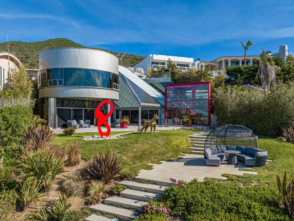 A futuristic grey home, with a red 8 in front, with a pathway.