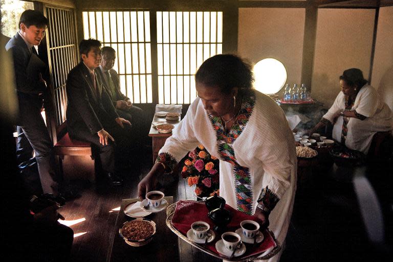 Japanese Prime Minister Shinzo Abe (L) sits with Ethiopian President Mulatu Teshome (2ndL) as they attend a traditional coffee ceremony in the Japanese garden of the National Palace in Addis Ababa on January 14, 2014