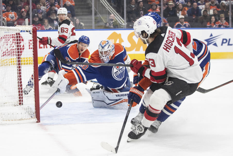 New Jersey Devils' Nico Hischier (13) is stopped by Edmonton Oilers' goalie Calvin Pickard (30) as Oilers' Vincent Desharnais (73) defends during first-period NHL hockey game action in Edmonton, Alberta, Sunday, Dec. 10, 2023. (Jason Franson/The Canadian Press via AP)