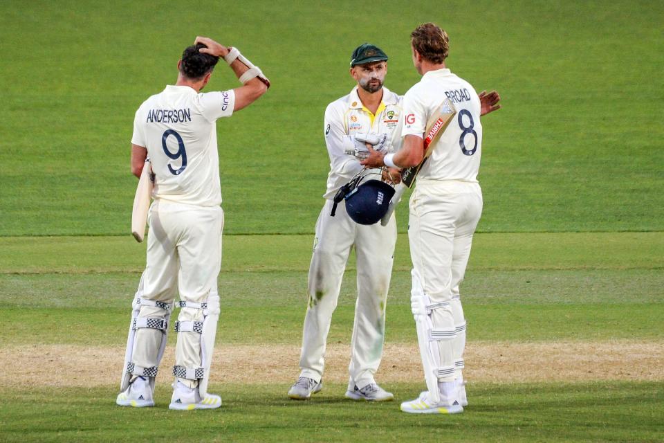 Australia's Nathan Lyon (C) shakes hands with England's last batting pair Jimmy Anderson (L) and Stuart Broad at the end of the second cricket Test match of the Ashes series at Adelaide Oval on December 20, 2021, in Adelaide. - -- IMAGE RESTRICTED TO EDITORIAL USE - STRICTLY NO COMMERCIAL USE -- (Photo by Brenton Edwards / AFP) / -- IMAGE RESTRICTED TO EDITORIAL USE - STRICTLY NO COMMERCIAL USE -- (Photo by BRENTON EDWARDS/AFP via Getty Images)