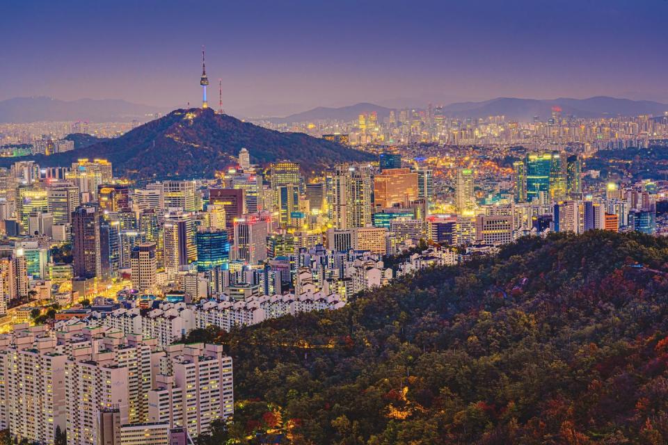 high angle view of namsan seoul tower surrounded by cityscape of seoul illuminated with lights in the twilight view from inwang mountain seoul, south korea