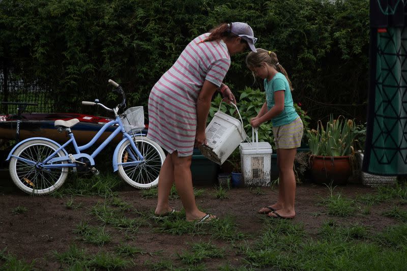 A mother and daughter use buckets of collected rainwater to water plants in the drought-affected town of Murrurundi