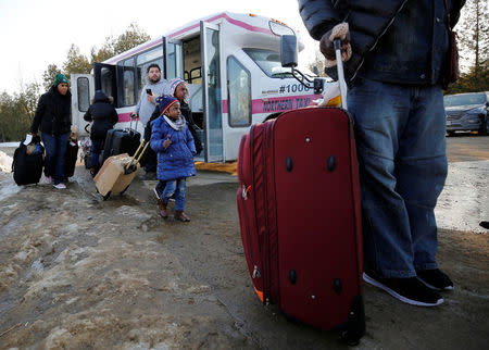 People gather with their luggage as they prepare to cross the US-Canada border into Canada in Champlain, New York, U.S., February 14, 2018. REUTERS/Chris Wattie