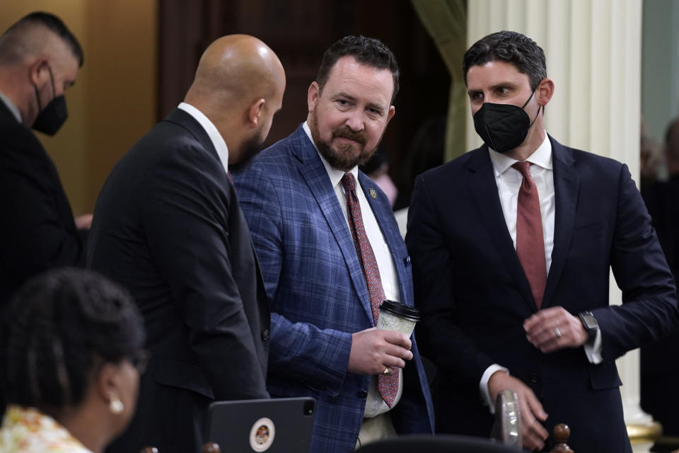 Assemblymembers, Isaac Bryan, D-Culver City, left Devon Mathis, R-Visalia and Jesse Gabriel, D-Encino, huddle as the Assembly works on budget bills at the Capitol in Sacramento, Calif., Wednesday, June 29, 2022. During an unusual night time session California lawmakers worked on a package of bills to enact the nearly $308 billion budget that includes cash payments for most taxpayers to help offset record high gas prices. (AP Photo/Rich Pedroncelli)