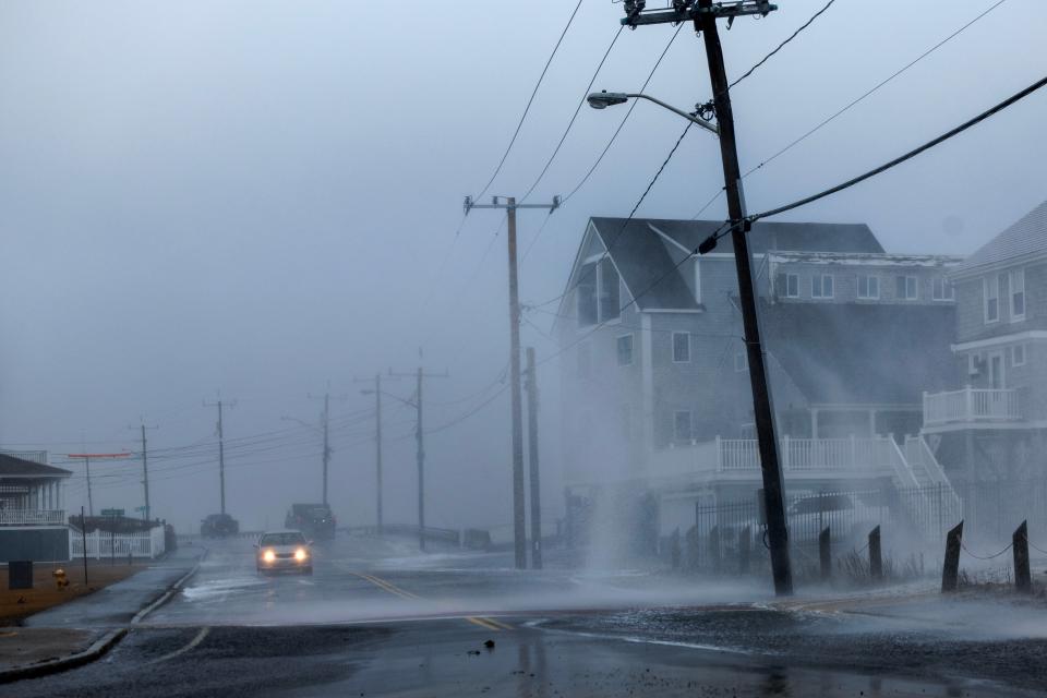 A driver makes their way through a water-covered street as waves crash over the seawall in Marshfield, Massachusetts, USA, 13 February 2024. A Nor'easter storm brought high winds and snow to the region (EPA)