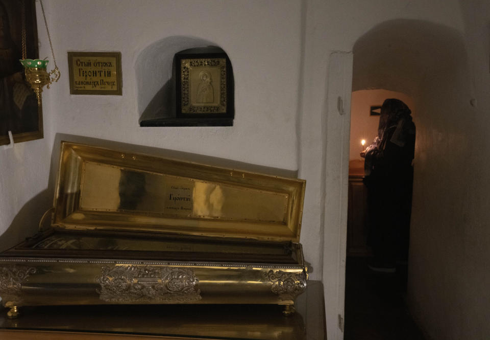 People pray at sarcophagi with holy relics in the underground labyrinth of the Monastery of the Caves, also known as Kyiv-Pechersk Lavra, one of the holiest sites of Eastern Orthodox Christians, in Kyiv, Ukraine, Friday, March 24, 2023. Tensions are on the rise at a prominent Orthodox monastery in Kyiv where the monks are facing eviction later this month. The Ukrainian government accuses the monks of links to Moscow, even though they claim to have severed ties with the Russian Orthodox Church following Russia's full-scale of invasion of Ukraine. (AP Photo/Efrem Lukatsky)