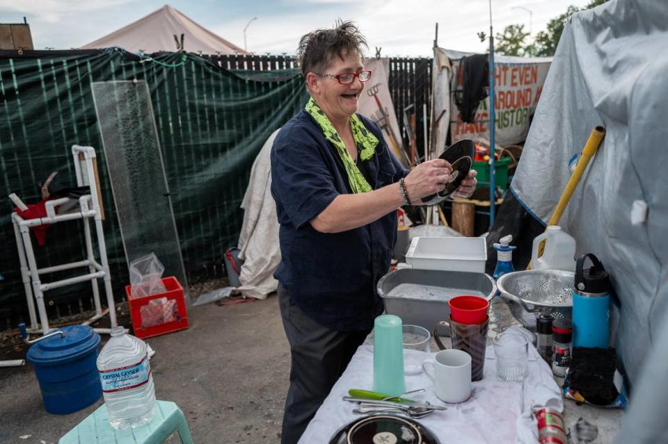 Joyce Williams washes dishes daily by heating plastic water containers in a pot on her propane gas stove at Camp Resolution last week. There is no water or electricity inside the city-provided trailers. The camp inhabitants use generators for fans to keep them cool and for lighting when the sun goes down. Renée C. Byer/rbyer@sacbee.com