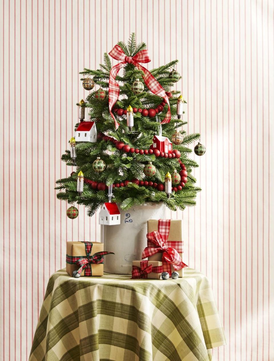 <p>Jazz up an entryway table with a mini balsam fir decorated with a plaid bow, cranberry garland, tartan ornaments, and clip-on candlesticks. A stoneware crock serves as a <a href="http://www.countryliving.com/shopping/g28857474/best-christmas-tree-stand/" rel="nofollow noopener" target="_blank" data-ylk="slk:tree stand;elm:context_link;itc:0;sec:content-canvas" class="link ">tree stand</a>. </p><p><a class="link " href="https://www.amazon.com/Kurt-Adler-Green-Plaid-Ornament/dp/B07R5458XH/ref=sr_1_24?dchild=1&keywords=plaid+ornaments&qid=1603138387&sr=8-24&tag=syn-yahoo-20&ascsubtag=%5Bartid%7C10050.g.1251%5Bsrc%7Cyahoo-us" rel="nofollow noopener" target="_blank" data-ylk="slk:SHOP ORNAMENTS;elm:context_link;itc:0;sec:content-canvas">SHOP ORNAMENTS</a></p>