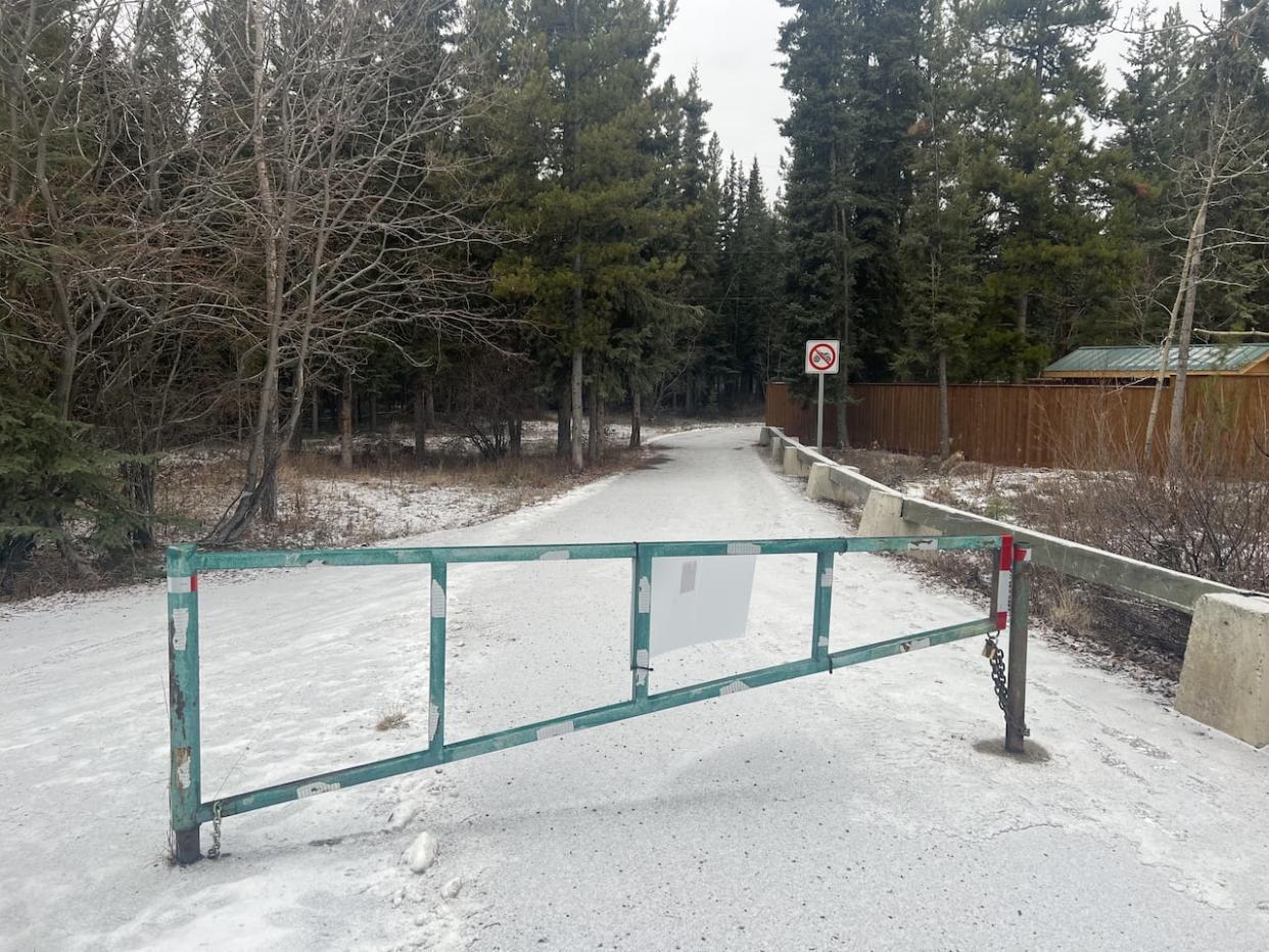 A closed and locked gate on a pathway in Whitehorse's Hillcrest neighbourhood. The gate had been open as part of a pilot project by the city, but will now remain closed. (Paul Tukker/CBC - image credit)