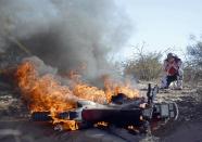 Paulo Goncalves of Portugal reacts in front of his Honda on fire during the fifth stage of the Dakar Rally 2014 from Chilecito to Tucuman, in this January 9, 2014 file photo. REUTERS/Stringer/Files (ARGENTINA - Tags: SPORT MOTORSPORT TPX IMAGES OF THE DAY)