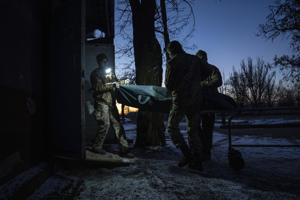 Ukrainian military medics carry a body of their killed comrade into a morgue in Donetsk region, Ukraine, Monday, Jan. 9, 2023. (AP Photo/Evgeniy Maloletka)