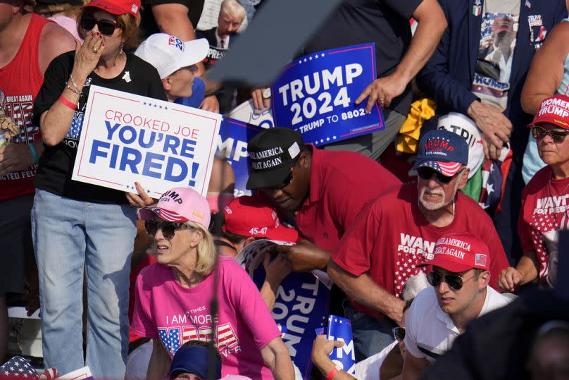 Members of the crowd react as US Secret Service agents surrounding Donald Trump at a campaign event in Butler, Pennsylvania, on Saturday, July 13, 2024.