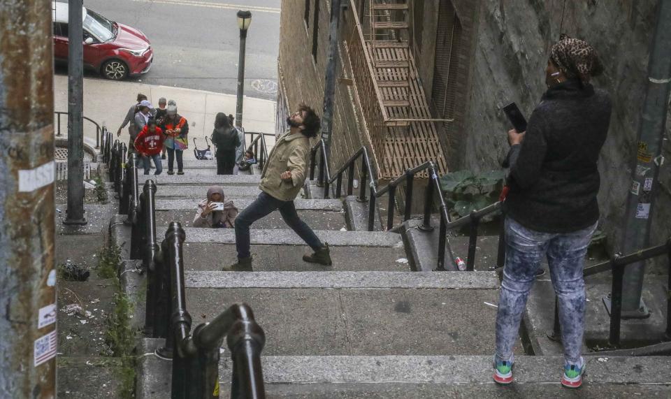 A man poses on the steps between two apartment buildings, Monday Oct. 28, 2019, in the Bronx borough of New York. The stairs have become a tourist attraction in recent weeks since the release of the movie “Joker.” In the movie, lead actor Joaquin Phoenix dances as he goes down the steps, wearing a bright red suit and clown makeup. (AP Photo/Bebeto Matthews)