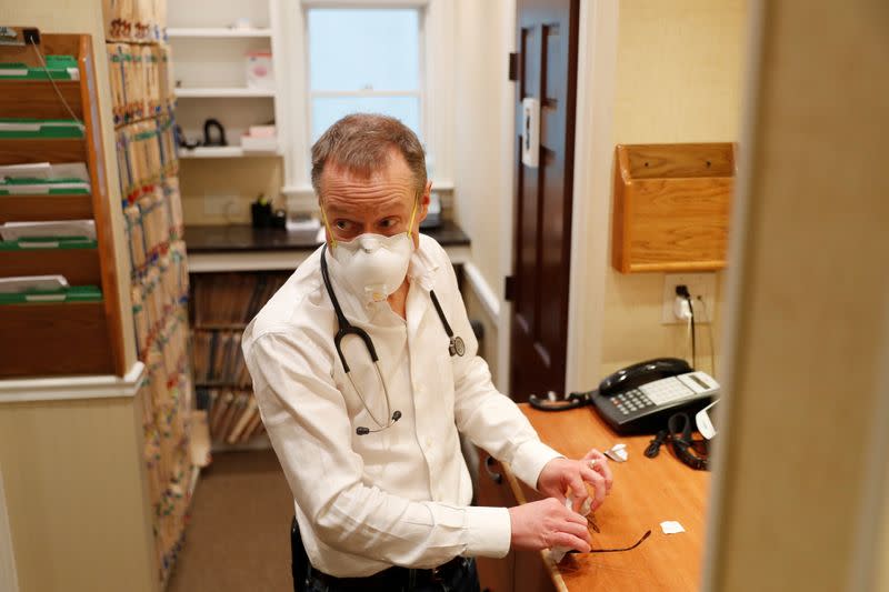 Dr Greg Gulbransen wipes his glasses while talking to a patient as he maintains visits with both his regular patients and those confirmed to have the coronavirus disease (COVID-19) at his pediatric practice in Oyster Bay, New York