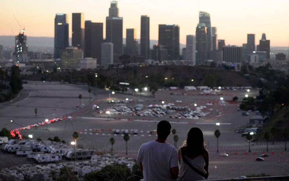 Visitors watch the sunset over a COVID-19 vaccination site at Dodger Stadium - AP