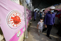 A man walks with his child after his son received a first dose of the Sinovac's COVID-19 vaccine at a health center outside Phnom Penh, Cambodia on Wednesday, Feb. 23, 2022. Cambodia began vaccinating 3- and 4-year-olds with the Chinese-made shots Wednesday after finding young children accounting for many new infections. Prime Minister Hun Sen appealed for parents to get their children vaccinated as soon as they can. (AP Photo/Heng Sinith)